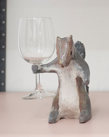 a ceramic sculpture of a squirrel holding a wineglass as if about to make a toast
